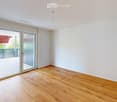Empty room with wooden flooring, white walls, and large sliding glass doors leading to a balcony or terrace.