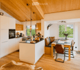 Open-plan kitchen and dining area with white cabinets, wooden ceiling, pendant lights, and a dining table with chairs.