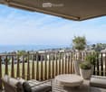 Balcony with a scenic view of a lake and town, featuring a lounge chair, a small table, and potted plants.