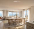 Modern open-plan living and dining area with large windows offering a scenic view, featuring a sofa, coffee table, dining table with chairs, bookshelf, and decorative vases.