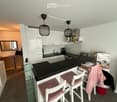 Modern kitchen with white cabinets, black countertops, a sink, a coffee maker, and two stools at the island.