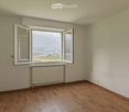 Empty room with wooden flooring, white walls, large window with open shutters, radiator, and a scenic mountain view.