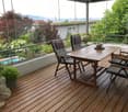 Wooden deck with a table, chairs, and potted plants, offering a scenic mountain view.