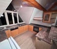 Modern kitchen with wooden cabinets, granite countertops, stainless steel appliances, and large windows.