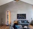 Modern living room with grey sofa, ottoman, coffee table, bookshelf, and artwork on the wall.