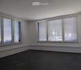 Empty room with white walls, dark tiled floor, and large windows with blinds.