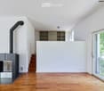 Modern living room with a sleek, grey fireplace, built-in shelving unit, large windows, and wooden flooring.