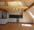 Modern kitchen with white cabinets, black countertop, stainless steel oven, and wooden flooring.
