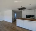 Modern kitchen with white cabinets, wooden countertop, and built-in oven. Large window offers a view of the outdoor area.