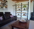 Modern living room with a dark leather sofa, wooden coffee table, floor lamp, bookshelf, and a fireplace.