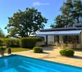 Outdoor patio area with a swimming pool, lounge chairs, dining table, and surrounding greenery.