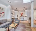 Modern living room with grey sofa, coffee table, armchairs, bar counter, and artwork.