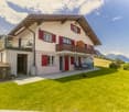Two story house, red shutters, balcony, parking place, lawn, mountain view