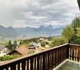 Balcony overlooking a scenic mountain landscape with houses and trees in the foreground.