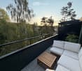 Balcony with a white sectional sofa, wooden coffee table, and lush greenery in the background.