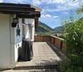Balcony with wooden railing, covered grill, and scenic mountain view.