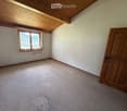 Empty room with wooden door, window with metal bars, and carpeted floor.