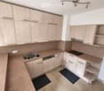 Modern kitchen with light wood cabinets, granite countertops, stainless steel sink and dishwasher, and built-in electric stove.