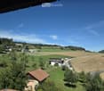 A scenic rural landscape with green fields, scattered houses, and a clear blue sky.