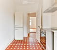 Modern kitchen with white cabinets, stainless steel appliances, and a hexagonal terracotta tile floor.