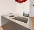 Modern kitchen with white cabinets, a stainless steel sink, a sleek induction cooktop, and a minimalist design.