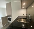 Modern bathroom with a dark granite countertop, stainless steel sink, and a built-in washing machine in a cabinet.