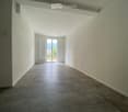 Empty hallway with tiled floor, white walls, and a large sliding glass door leading to an outdoor area.