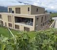 Modern two-story house with large windows, a balcony, and a well-maintained garden.