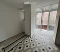 Hallway with hexagonal tile flooring, leading to a balcony area with glass doors and a view of a tiled roof.