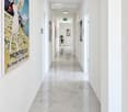 Modern hallway with white walls, polished marble floor, recessed lighting, and framed artwork, including a large poster titled "Montreux."
