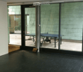 Modern interior with dark flooring, large glass sliding doors leading to an outdoor area, and a small table and chair set near the entrance.