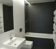 Modern bathroom with black tiled walls, white fixtures, and a sleek design.