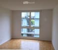 Empty room with wooden flooring and large sliding glass doors leading to a balcony area.