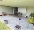 Outdoor patio area with gravel ground, wooden deck, small table and chairs, potted plants, and decorative items.
