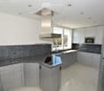 Modern kitchen with white cabinets, granite countertops, stainless steel appliances, and a large window providing natural light.