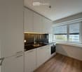 modern kitchen with white cabinets, black countertops, stainless steel sink, oven, window with blinds