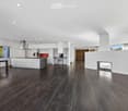 Modern open-concept kitchen and living area with dark hardwood floors, white cabinets, stainless steel appliances, and a built-in fireplace.