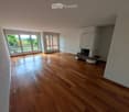 Empty room with wooden flooring, large windows, and a fireplace with a bench.