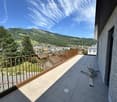 Balcony with tiled floor, wooden railing, and scenic mountain and town view.