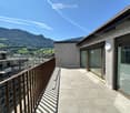 Balcony with modern glass doors, wooden railing, and a scenic mountain view in the background.