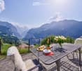 Furniture set on the balcony includes a table, chairs and tableware, overlooking a mountain valley