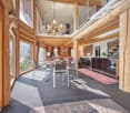 Dining area with round table, chandelier, sofa, cabinets, wooden columns, glass windows