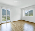 Empty room with wooden flooring, white walls, large windows, and a sliding glass door leading to a balcony with a scenic mountain view.