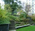 A landscaped garden with steps, greenery, and a small play structure in the background.