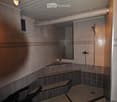 Modern bathroom with tiled walls and floor, built-in benches, a shower area, and a mirror above a small shelf.