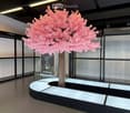 Modern interior with a large artificial cherry blossom tree in the center, surrounded by sleek black and white furniture and glass display cases.
