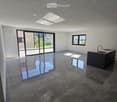 Empty room with dark stone tiles, large windows, and a modern kitchen island with a sink.