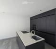 Modern kitchen with white countertop, black cabinets, and a stainless steel sink and faucet.