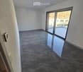 Empty room with dark grey tiled floor, white walls, and large sliding glass door leading to a balcony.