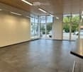 Empty room with tiled floor, large windows, and a door leading outside. No furniture or equipment present.